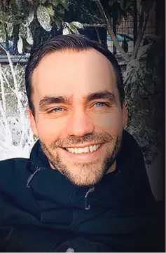 Man met blauwe ogen en baard lacht in de sneeuw