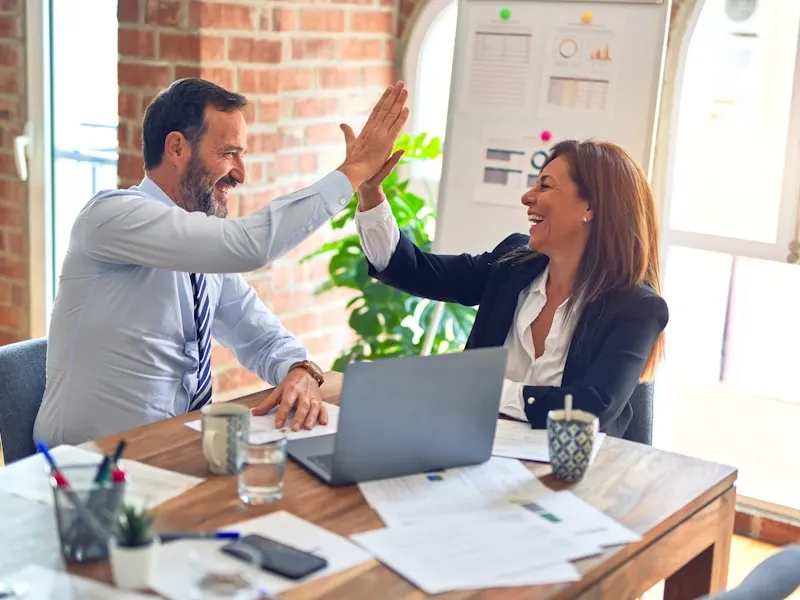 Zakelijke collega's vieren succes met high-five in kantoor
