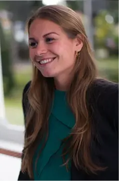 Lachende vrouw in groen met zwarte blazer